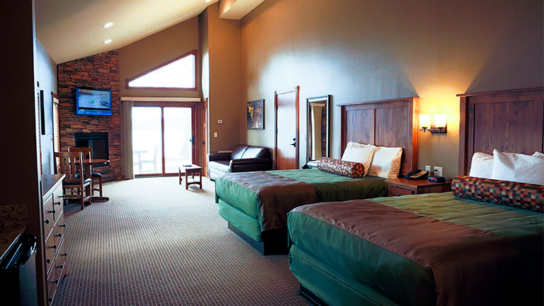 cabin room with two queen size beds, a leather couch, a fireplace, and television set