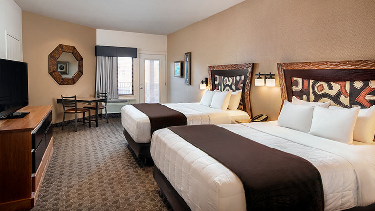 An interior of a Kalahari Resorts hotel room featuring double queen beds and a balcony.