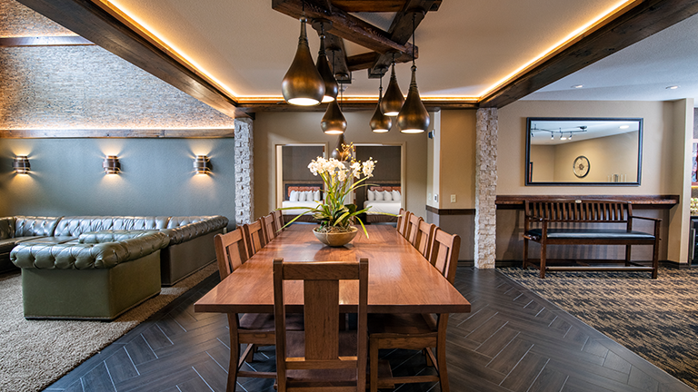 an overview of inside the Big Five Suite. Consists of a bedroom with dining area, kitchen, and a pool table.