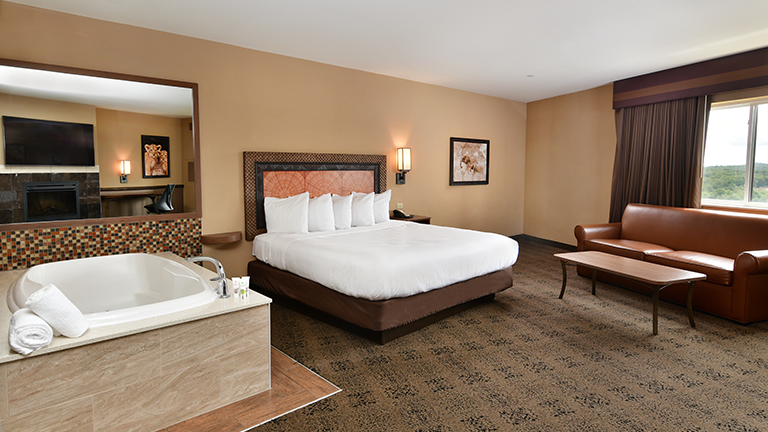 an overview of inside the Whirlpool Room. Consists of whirlpool tub, fireplace, tv, mini fridge, and microwave.