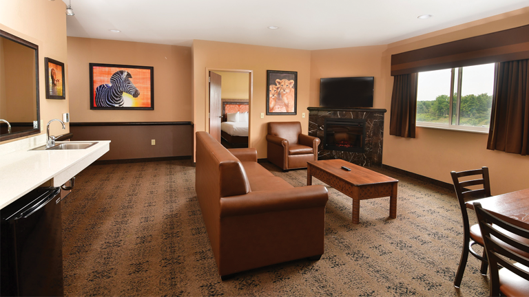 an overview of inside the 3 Bedroom Family Suite. Consists of a kitchen area, fireplace, a dining area, a couch, and a table.