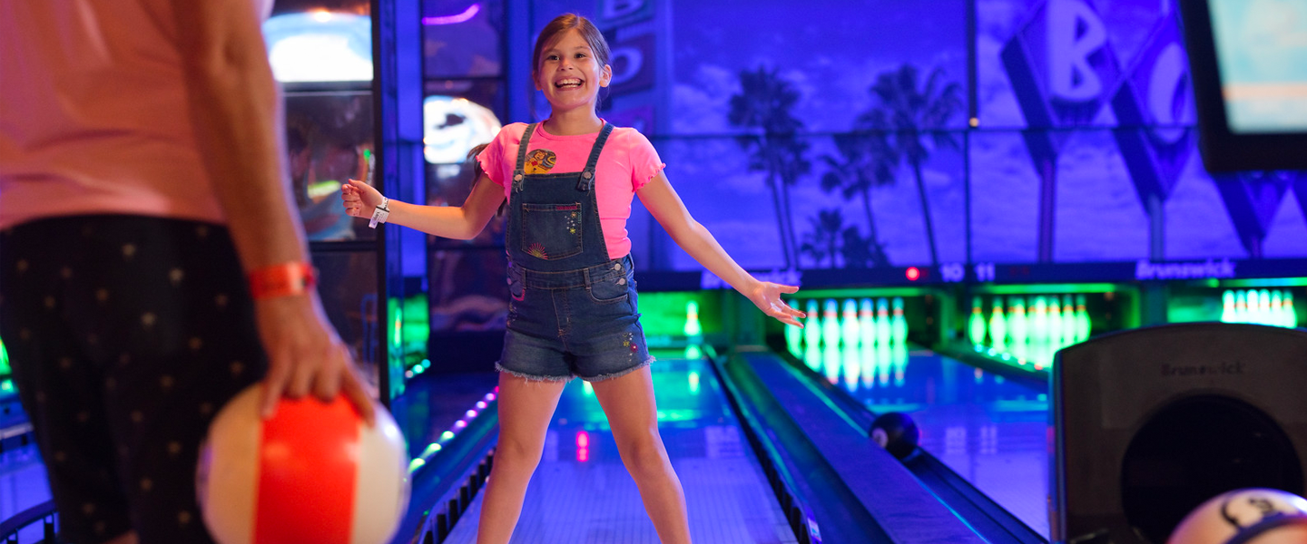 A happy little girl bowling.